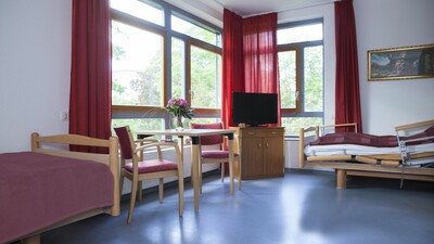 Blick in individuell eingerichtetes Doppelzimmer mit Betten und Sitzgelegenheit